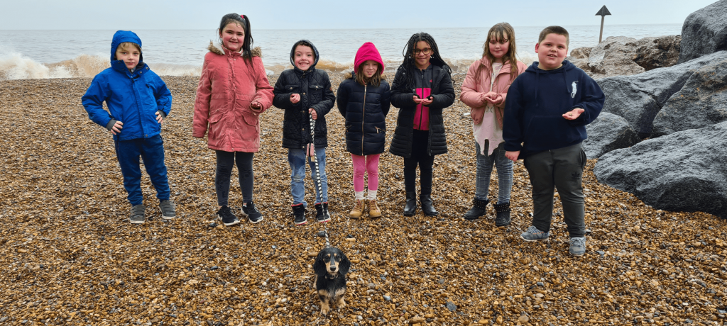 pupils walking school dog on a pebbly beach